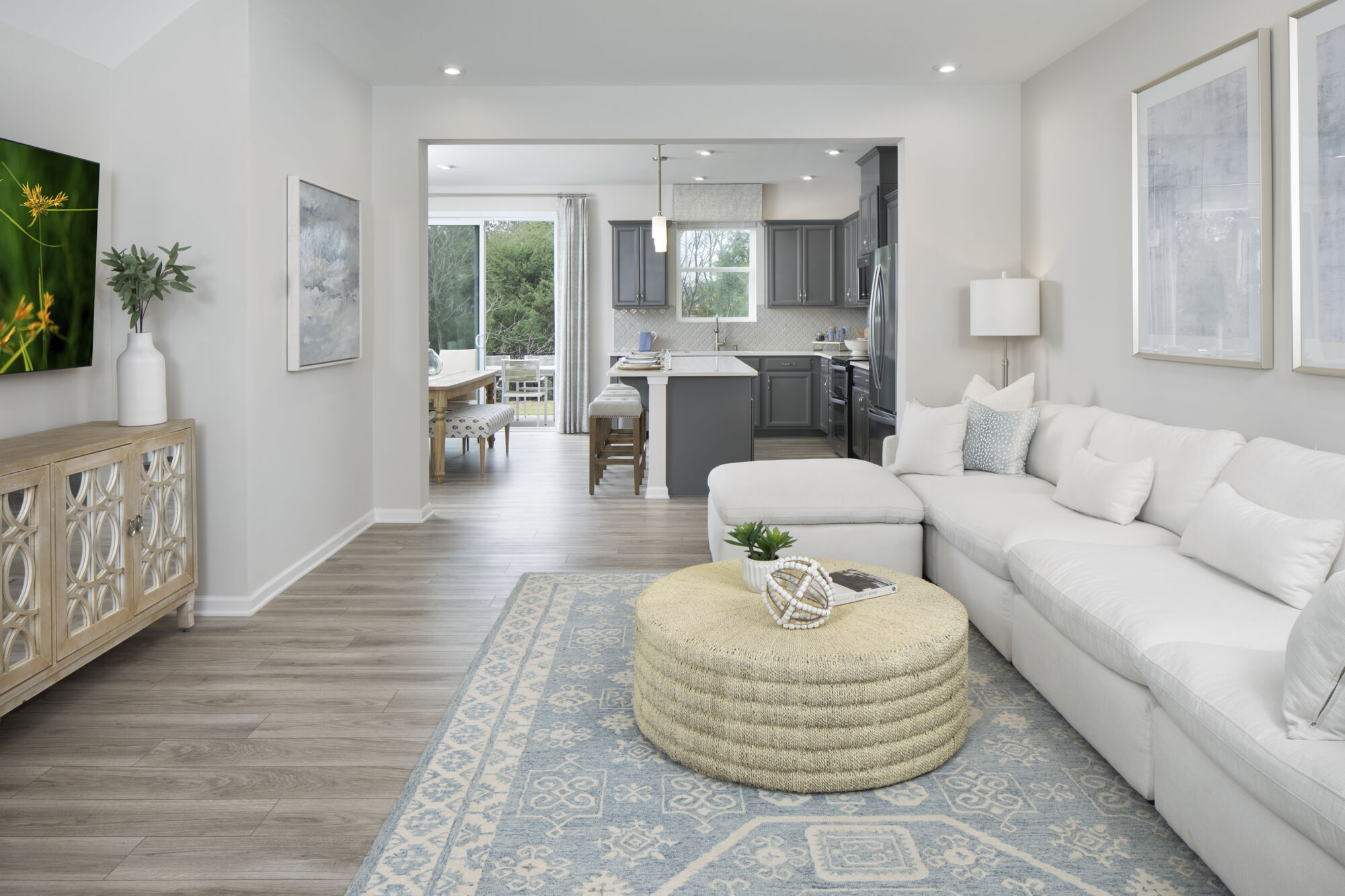 Greatroom with painting, door, curtains, window, rug, refrigerator, dark wood cabinets, wood flooring and pendant light